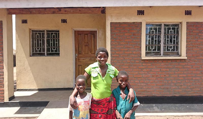 Home owner Estina Banda with her new home in Malawi 