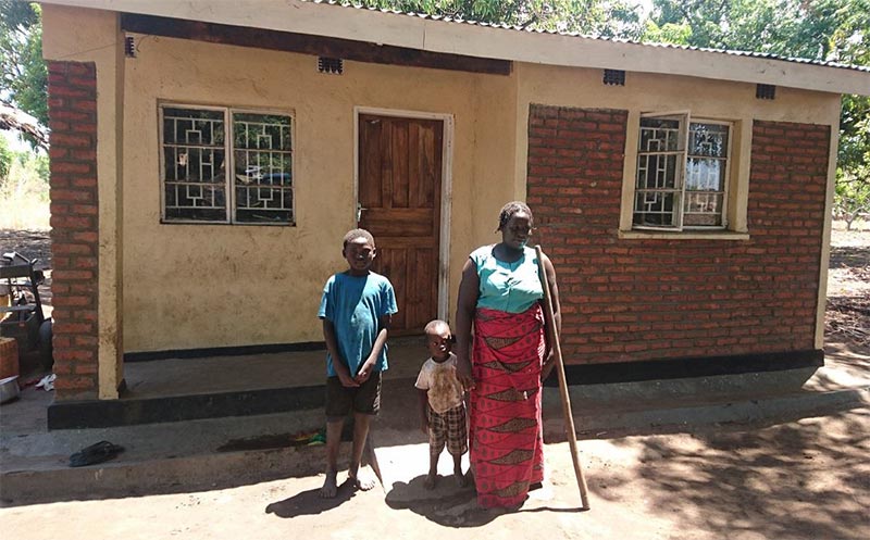 Home owner, Regina and her family outside their home in Malawi