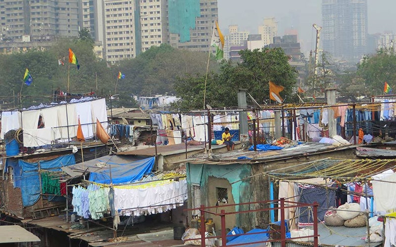 shacks in India's slums with urbanisation evident in the background