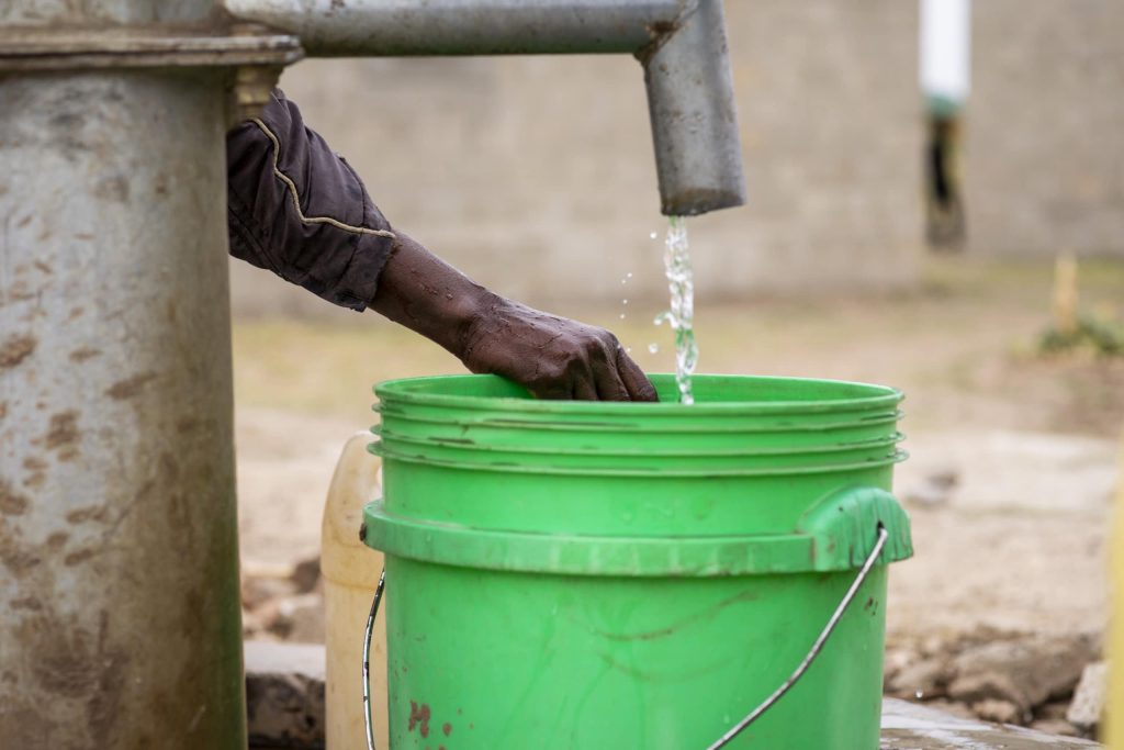 water falls into a green bucket in Malawi