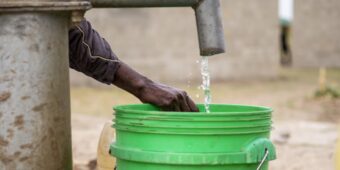 water falls into a green bucket in Malawi