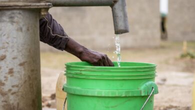 water falls into a green bucket in Malawi