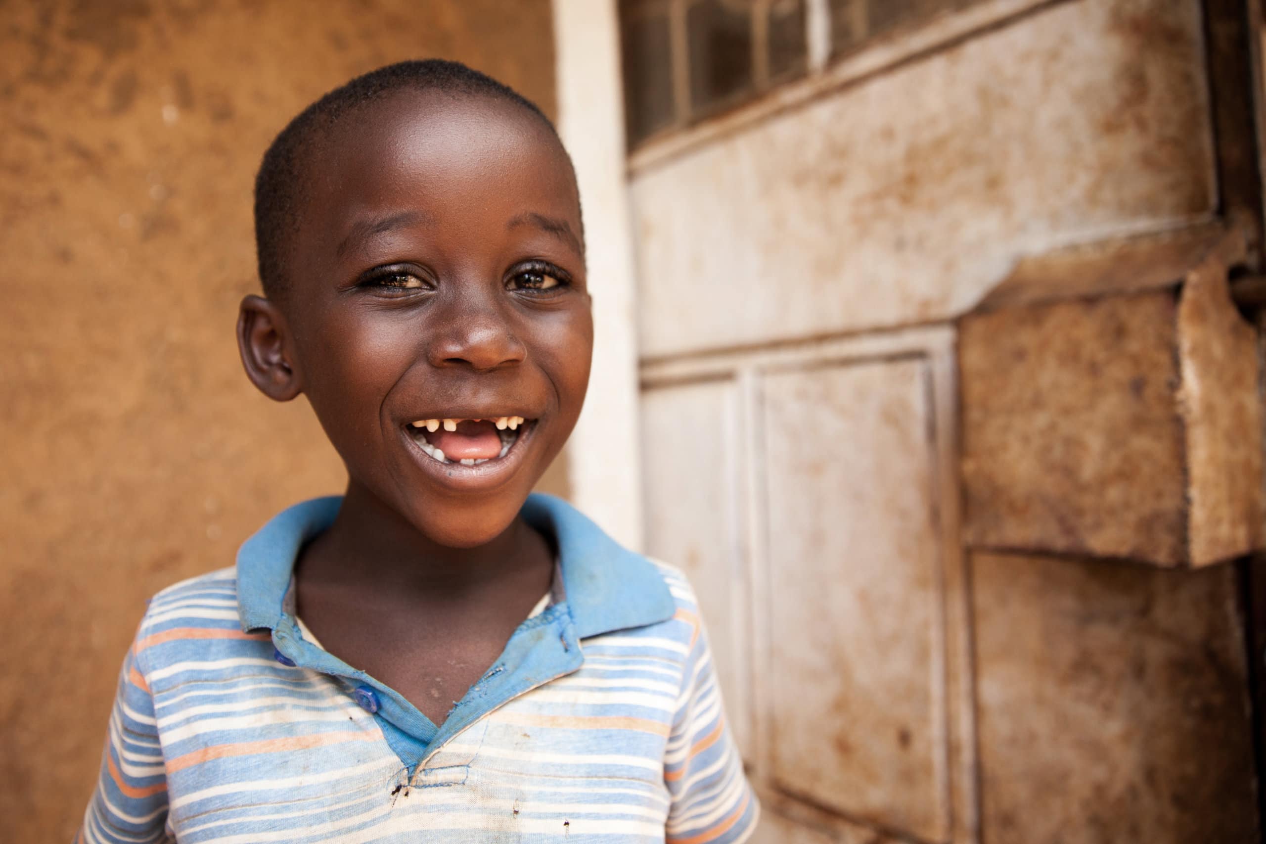boy in kenya smiles for camera in blue shirt