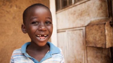 boy in kenya smiles for camera in blue shirt