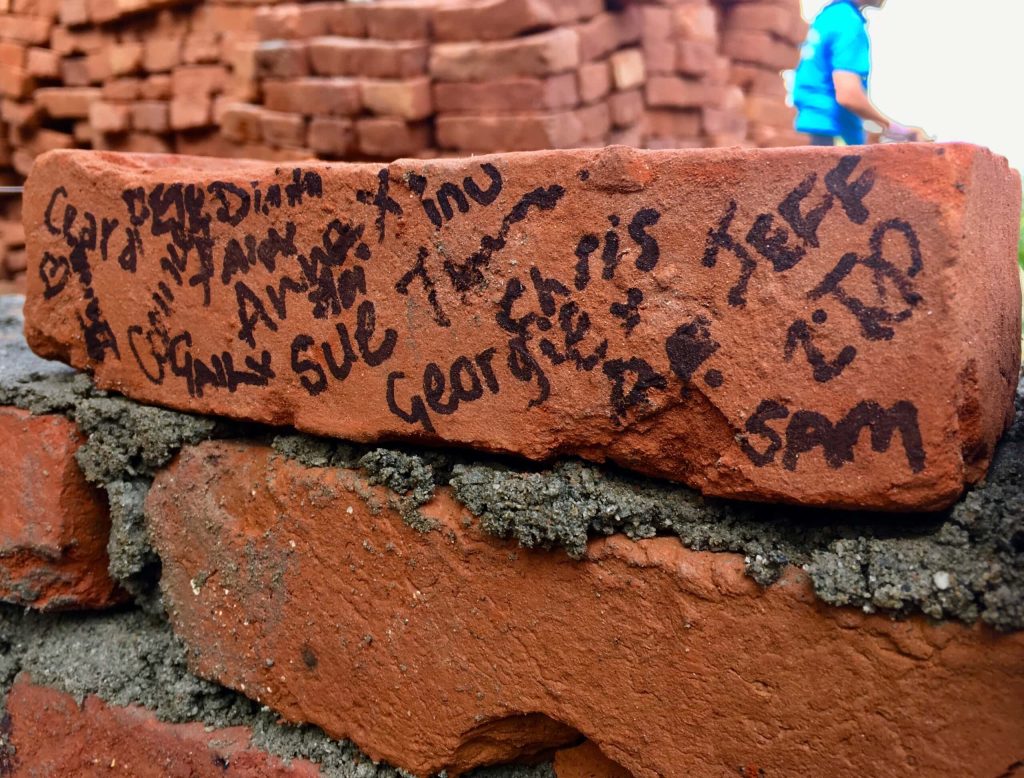 people working on the charity project have signed a brick with their names