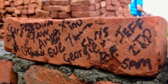 people working on the charity project have signed a brick with their names