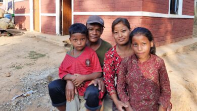 a family sit together outside their new house