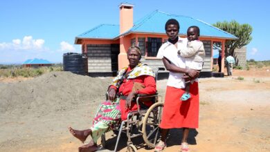 kenya family are together - woman on the left sits in a wheelchair beside a mother and baby