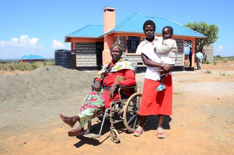 kenya family are together - woman on the left sits in a wheelchair beside a mother and baby