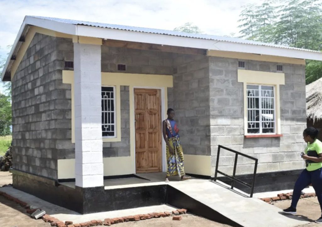 person in Malawi gather around a new Habitat for Humanity home