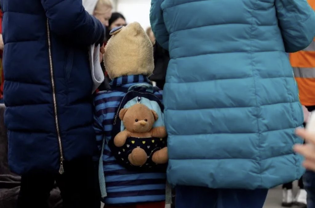 refugee child with teddy on his back from Ukraine