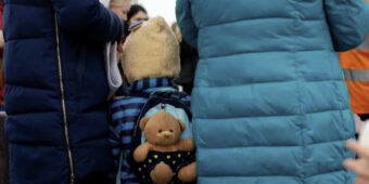 refugee child with teddy on his back from Ukraine