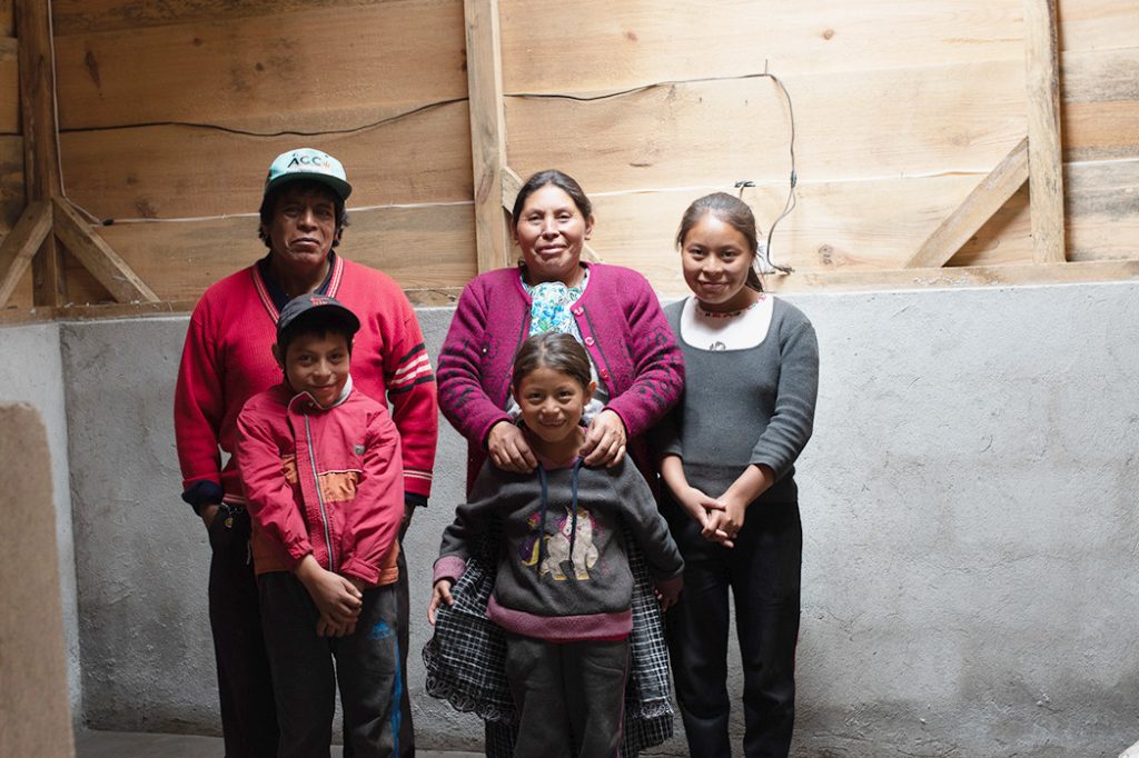 Maria and her children stand in a room within their new hybrid home in Guatemala