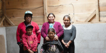 Maria and her children stand in a room within their new hybrid home in Guatemala