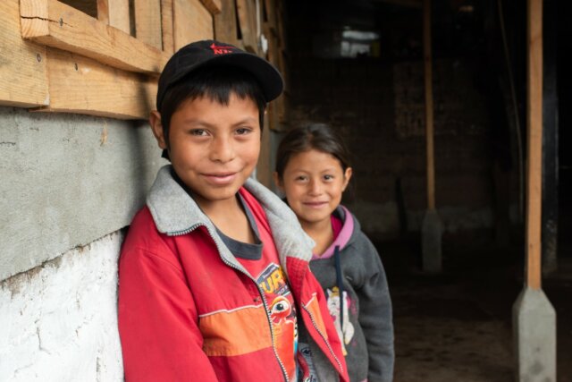 Two of Maria's children stand outside their new hybrid home in Guatemala