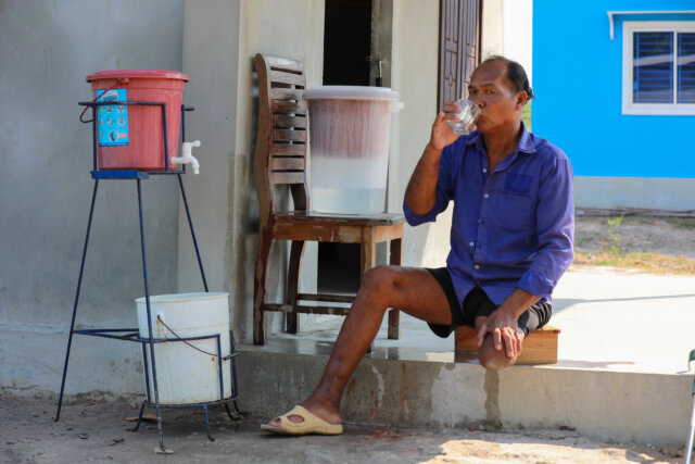 Growing Homes Together - Khon, who lost his leg, sits outside his new home