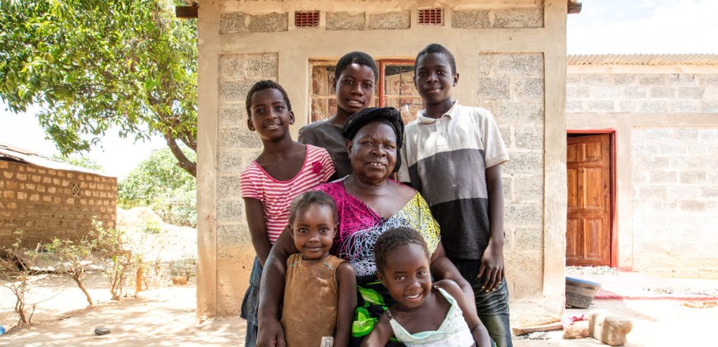 Yoanna and grandchildren outside their house