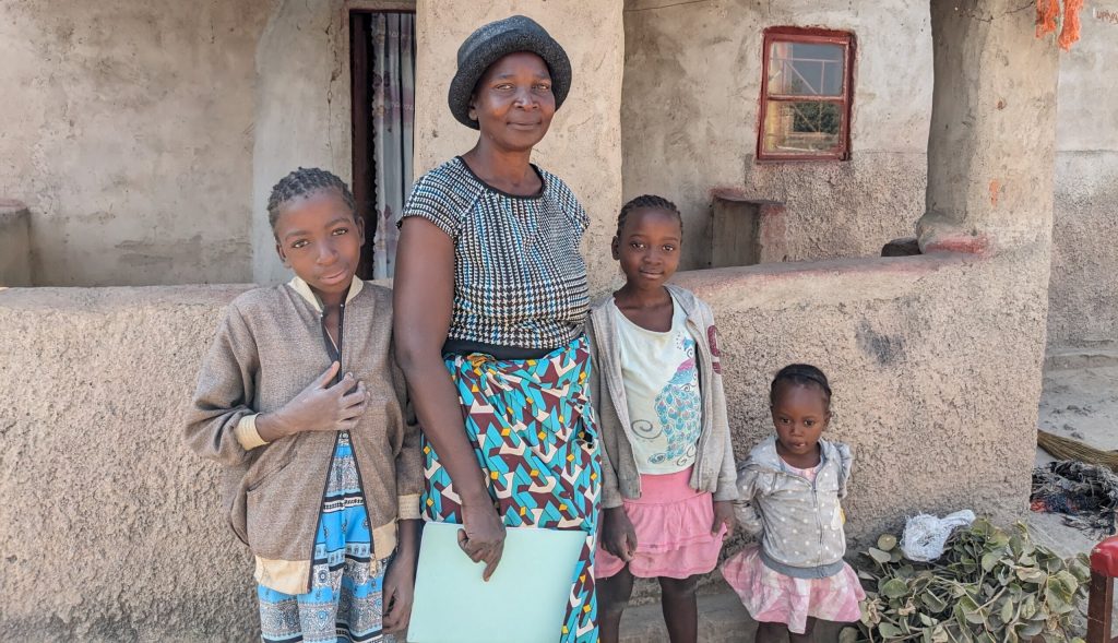 Tasila outside her house in Makalulu, Zambia with her family