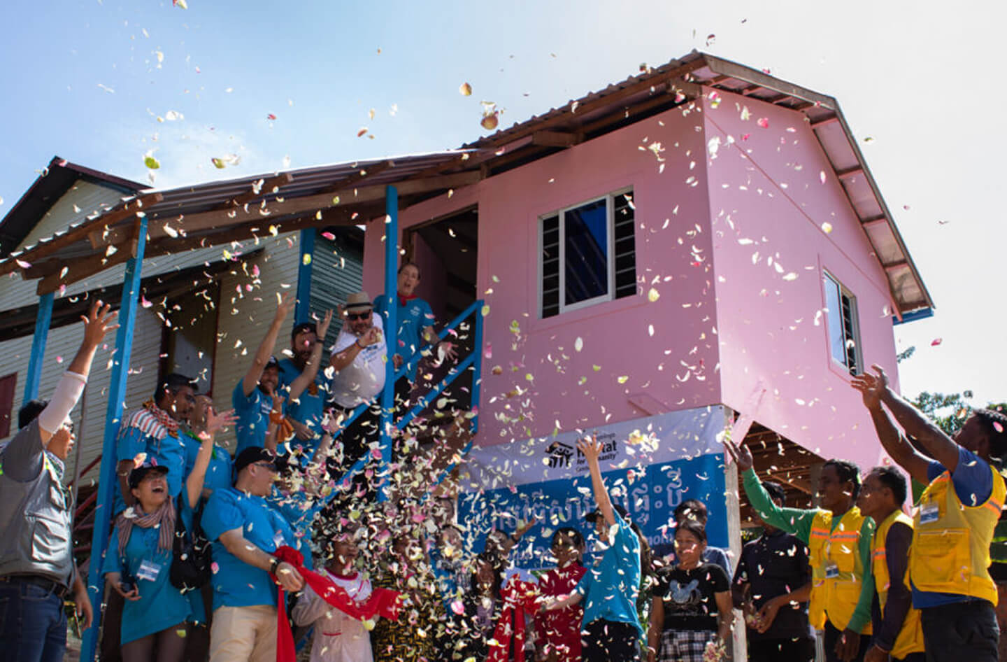 A crowd celebrating with confetti outside a pink building