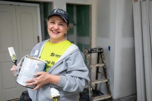 A Habitat volunteer holding a tin of paint, ready to decorate a home