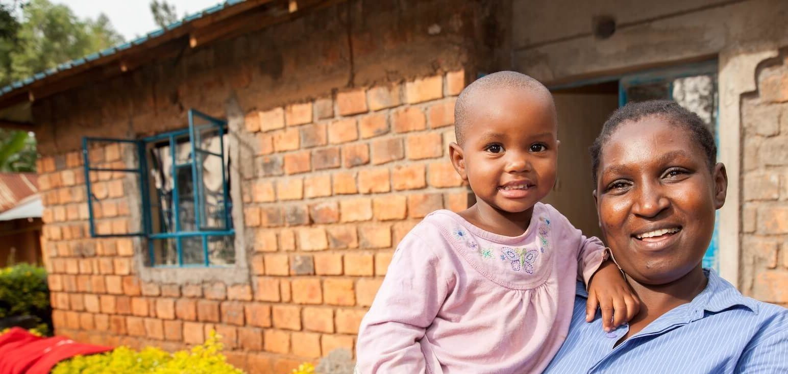A Habitat homeowner holding their child outside their newly built home