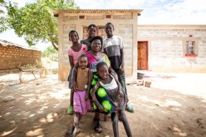 A family sit outside their Habitat home in Zambia
