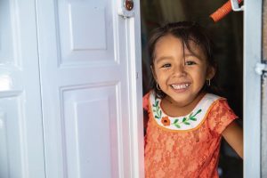 A child smiles from the doorway of her new Habitat home in Mexico