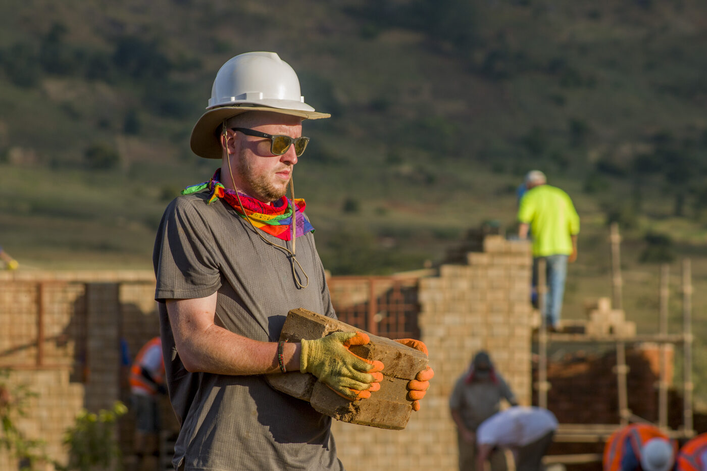 A volunteer carrying bricks on a Global Village build
