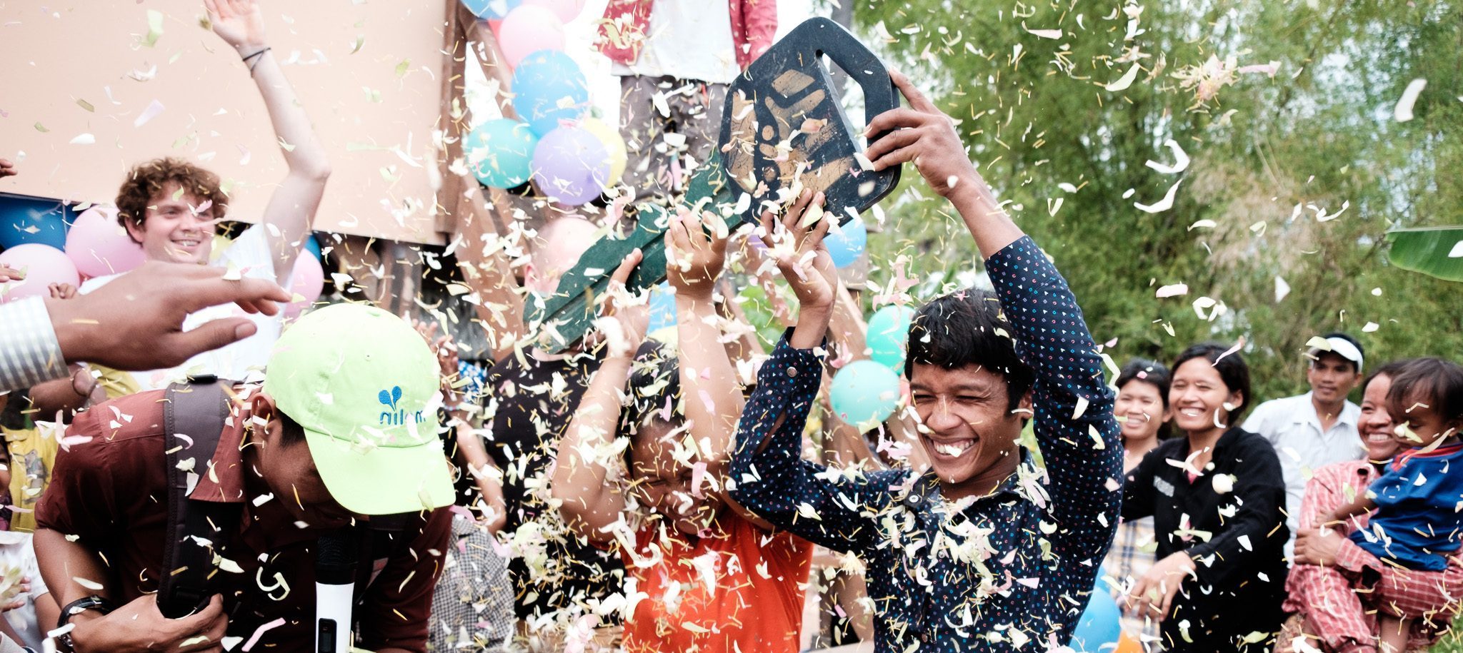Families in a Cambodian community celebrating with confetti at a Habitat for Humanity build
