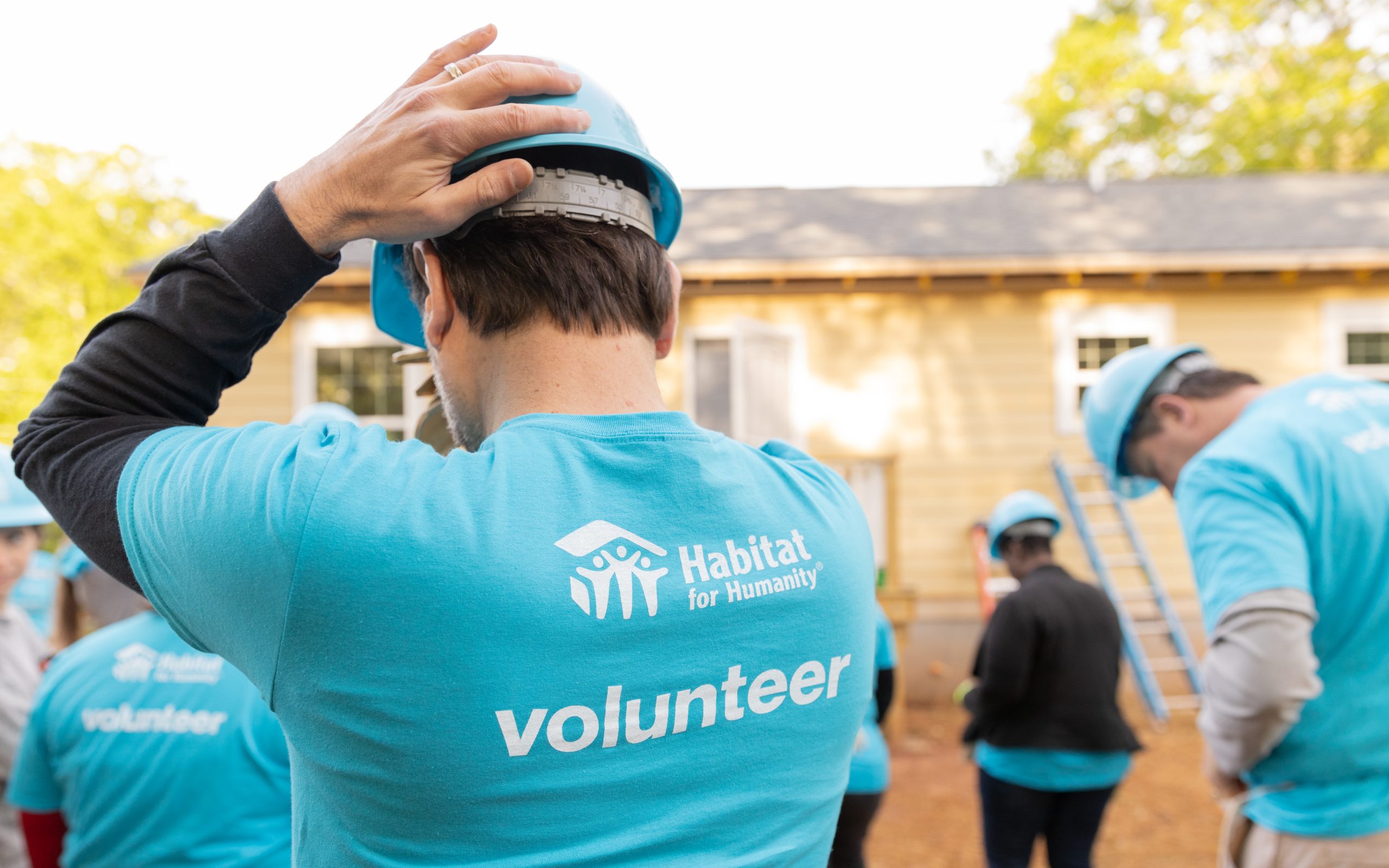A Habitat volunteer in a branded top at an outdoor build