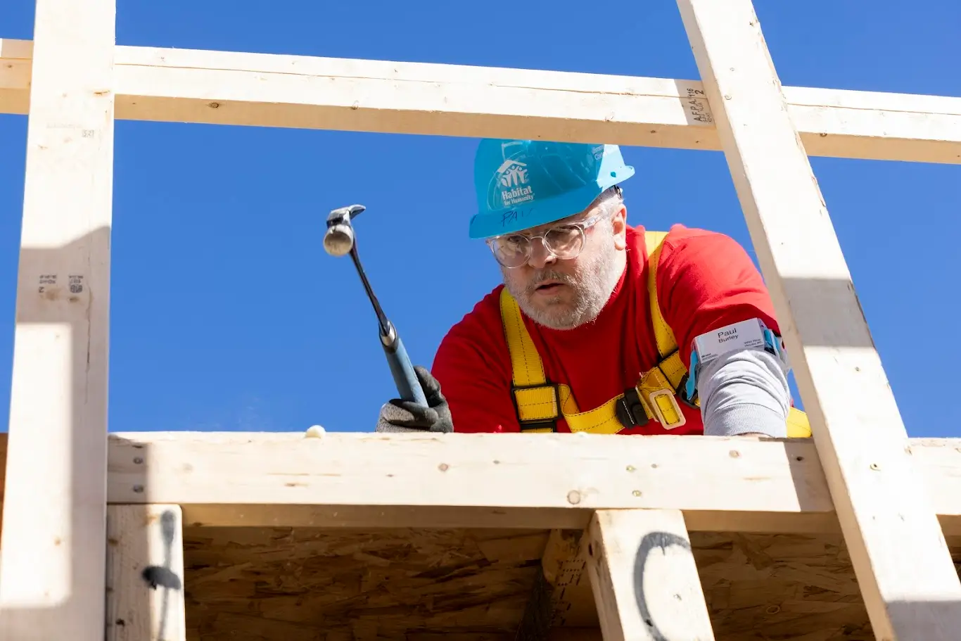 Volunteer using a hammer to build a timber-framed Habitat for Humanity home