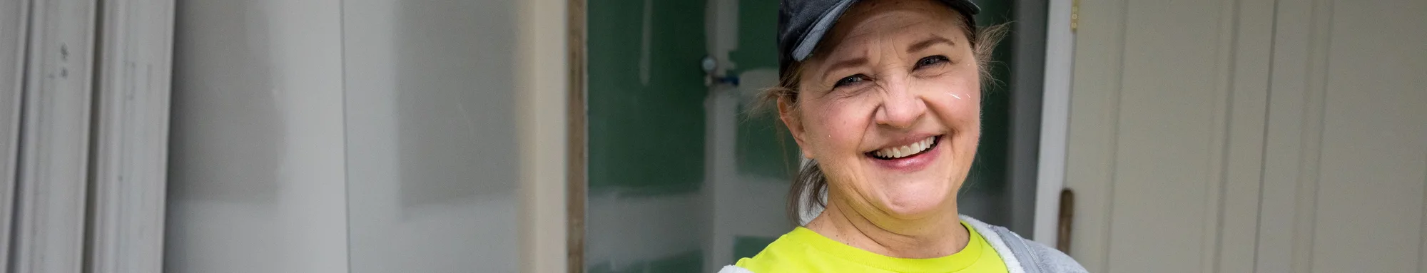 A smiling volunteer in a yellow top outdoors