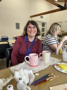 Two women smiling at a table during a Habitat mug-painting workshop