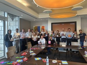 A corporate volunteering team gathered behind a table of craft materials at a Habitat event