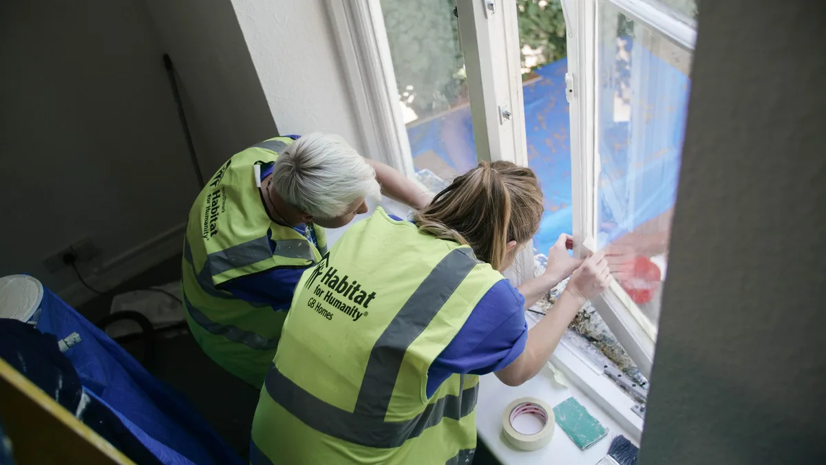 Volunteers in hi-vis vests working by a window indoors