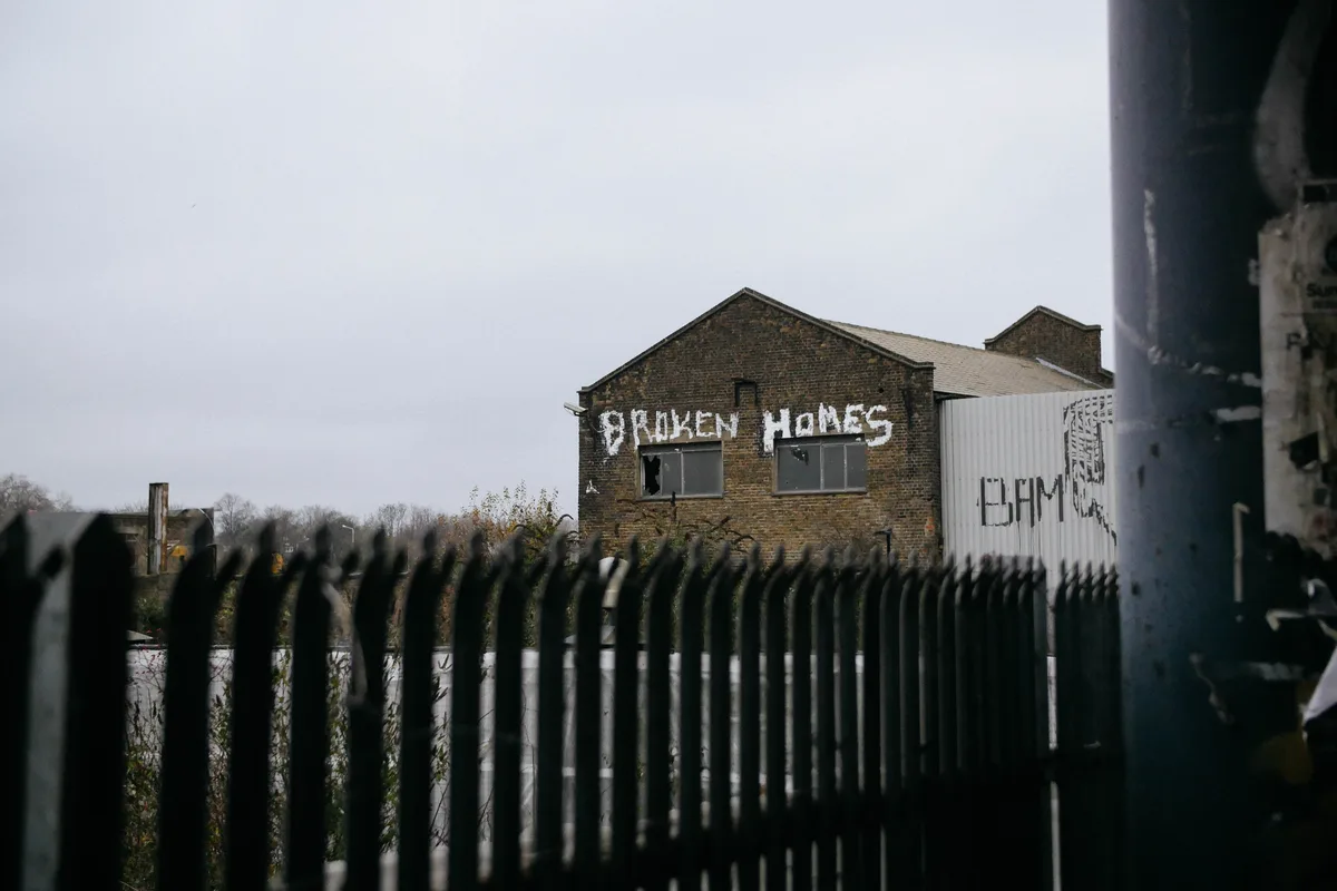 An abandoned building, with the words 'broken homes' graffitied onto the outside