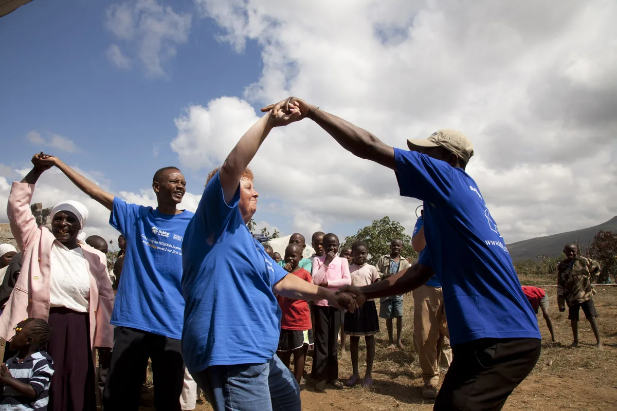 A group of people joining raised hands in celebration outdoors