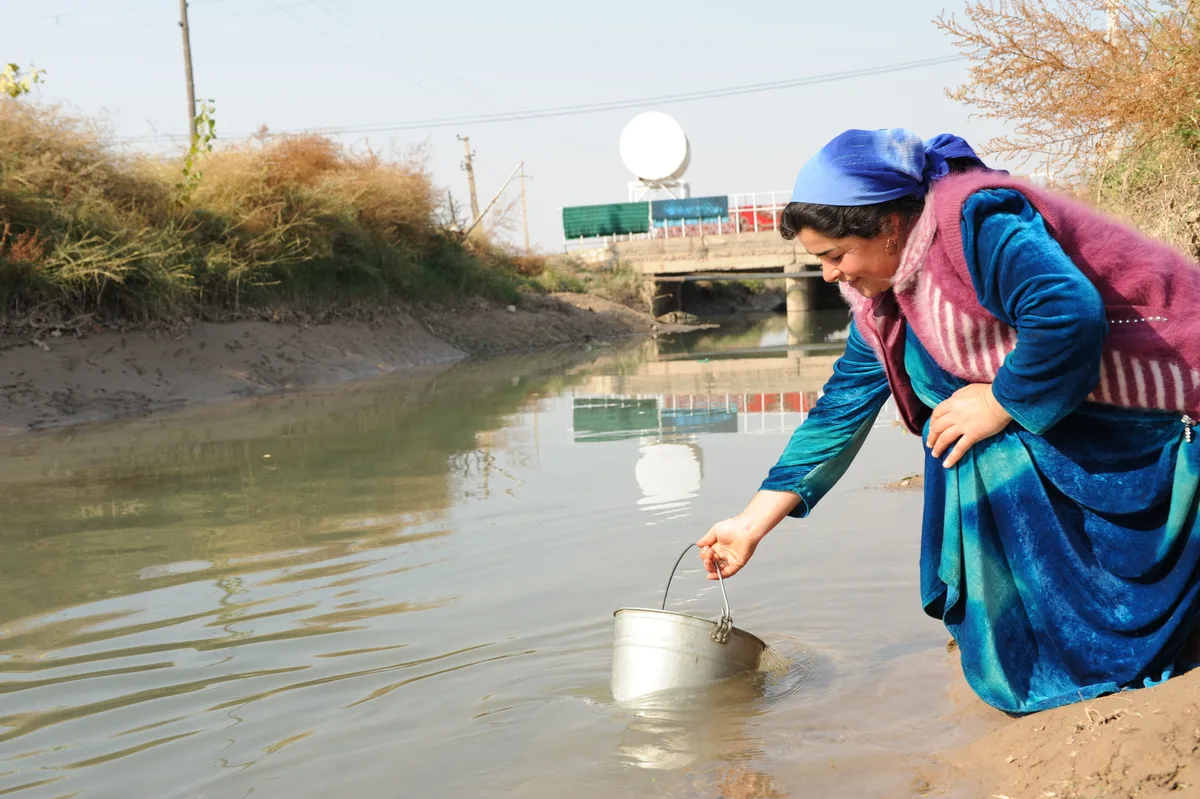 A single mother collecting water from a river in a community without clean water