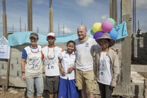 Volunteers and a local family celebrating with balloons at a Habitat build site